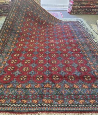 Handmade Afghan Bokhara, Size: 288 x 230 cm, in rich madder red with a traditional “gol” (elephant’s foot) pattern, High-quality wool on a durable cotton foundation.