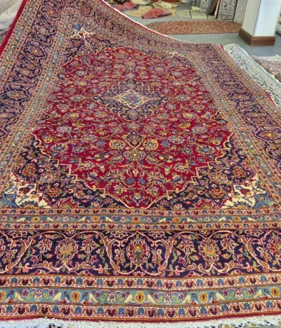 Floral traditional Hand-knotted Kashan rug, Size: 380 x 250 cm, High-quality wool pile on a sturdy cotton foundation, Rich crimson red field contrasted by a deep navy blue border.