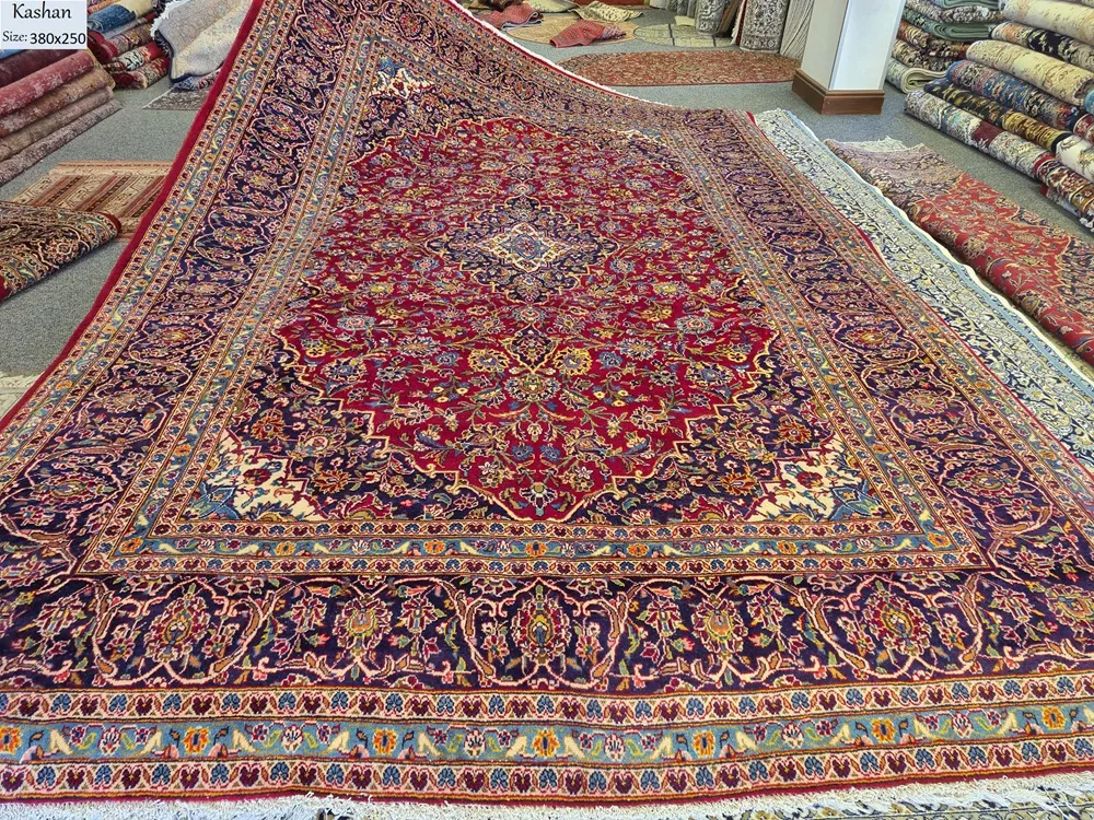 Floral traditional Hand-knotted Kashan rug, Size: 380 x 250 cm, High-quality wool pile on a sturdy cotton foundation, Rich crimson red field contrasted by a deep navy blue border.