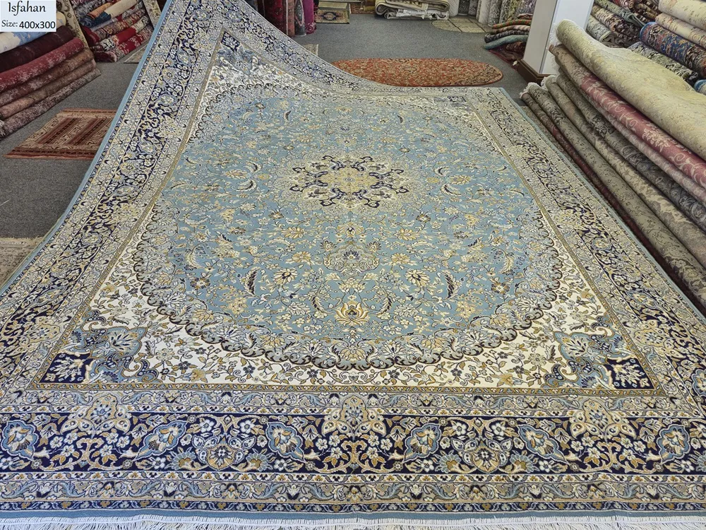 This exquisite 400 x 300 cm Isfahan rug features a classic central medallion layout, framed by an elegant navy blue border and a soft ivory/light blue field. Inspired by the Safavid-era tilework of Isfahan’s grand mosques, the design utilizes flowing Shah Abbasi floral motifs and complex arabesque vines.