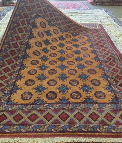 Hand-knotted Bokhara rug, Size 189 x 146 cm, repeating octagonal medallions (Guls) and star motifs, AmberGolden-Orange field with Cobalt Blue, High-quality wool on a durable cotton foundation.