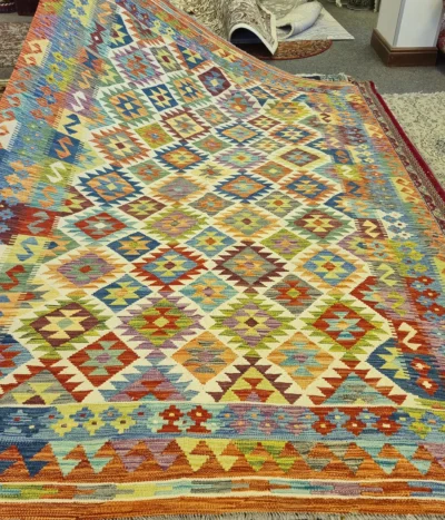 Handwoven Kilim rug, Size: 294 x 197 cm, Traditional geometric diamond motifs. Rich tapestry of turquoise, sunset orange, deep crimson & earthy mustard tones.