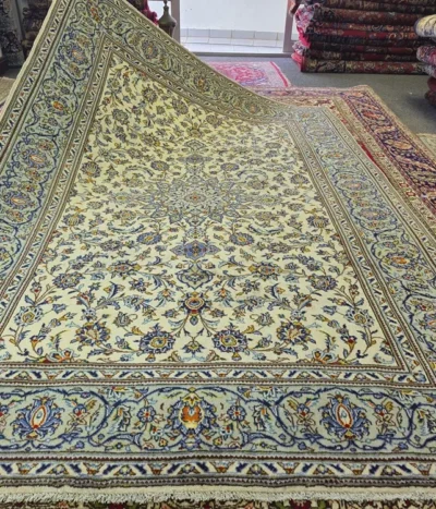 Elegance Hand-knotted Persian Kashan carpet, Size: 296 x 204 cm, Featuring a luminous ivory field, the design is anchored by a magnificent central medallion, surrounded by an intricate dance of Shah Abbasi floral motifs and delicate vine scrolls, Premium quality wool on a cotton foundation.