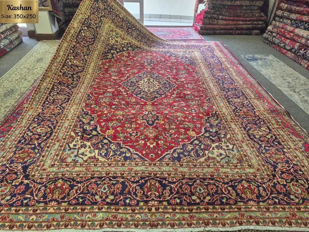 Handmade Kashan Persian rug, Size: 350 x 250 cm, Features a classic central floral medallion surrounded by a rich red field and an intricate navy blue border, fine wool & vegetable dye.
