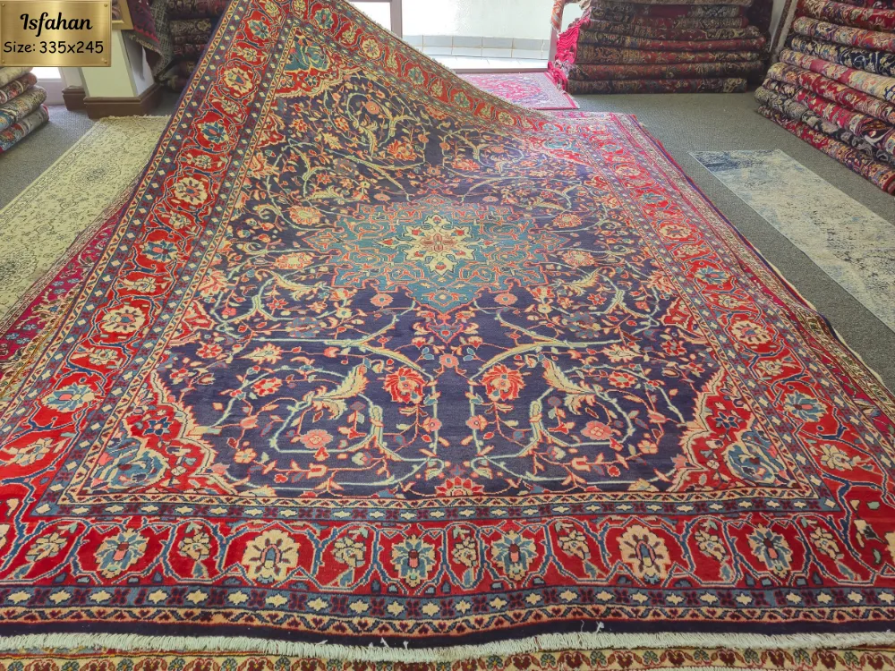 Vintage hand-knotted Persian Isfahan carpet, Size: 335 x 245 cm, central medallion surrounded by traditional floral patterns on a deep navy field and framed by a rich red border, wool on a durable cotton foundation.