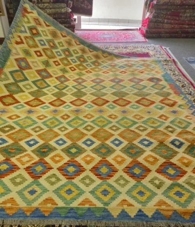 Hand-Woven Afghan Kilim, Size: 296 x 247 cm, Traditional geometric diamond medallions, vibrant harmony of sun-warmed gold, sage green, terracottas, and vibrant blues, 100% Hand-spun Wool on a Wool foundation.
