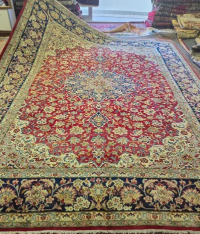 Hand-knotted Mashhad Persian Carpet, Size: 375 x 298 cm, rich red field adorned with intricate floral and scrollwork motifs, beautifully contrasted by a deep navy blue and ivory border, wool on a cotton foundation.