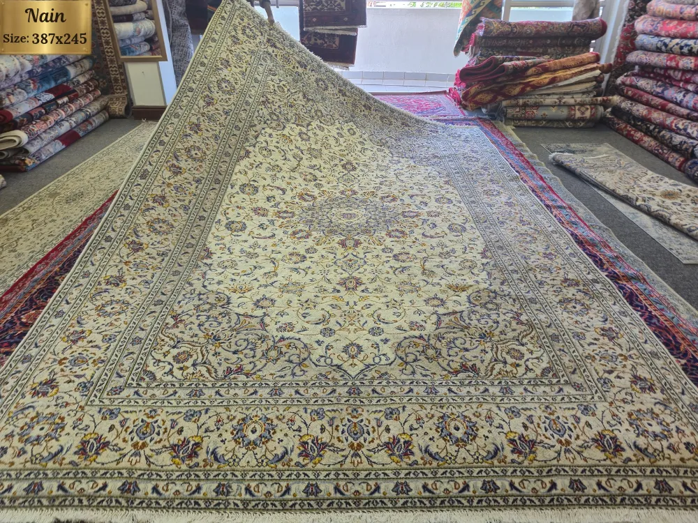 Hand-Knotted Persian Nain carpet, Size: 387 x 245 cm. refined ivory and cream foundation adorned with intricate floral motifs and delicate blue, gold, and burgundy accents, wool pile on cotton foundation.