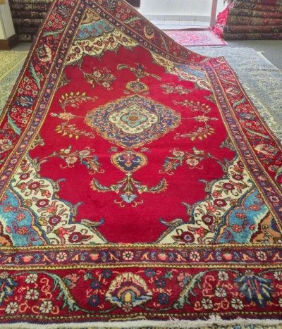 Persian Tabriz carpet, Size: 330 x 193 cm, floral motifs in rich crimson red field framed by light blue & ivory accents Hand-knotted with durable, high-density wool construction.